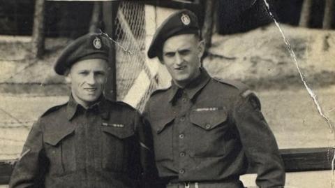 Old black and white photo of two soldiers in army uniform, including berets, posing for the camera