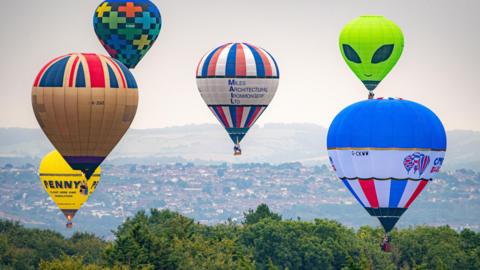 Different coloured balloons fill up the sky on a hazy day