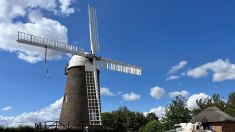 A windmill with heavy machinery in the foreground