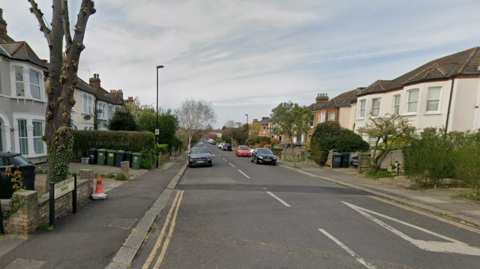 A Google streetview image of a residential road with cars parked on either side