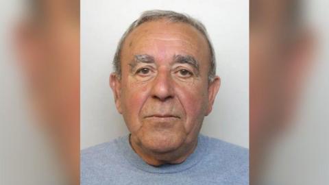 Custody image of Peter Lazarides - an man in his 70s, wearing a grey jumper. He has grey hair.