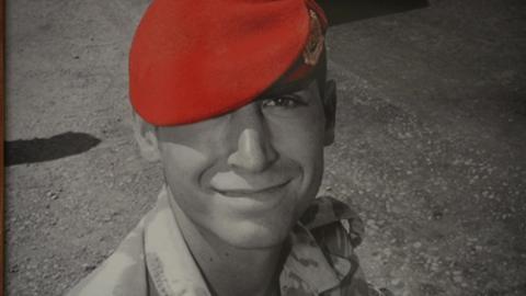 A picture of Corporal Simon Miller shows him smiling and in full uniform. His cap is red.