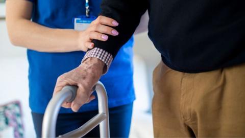 Elderly person helped walking