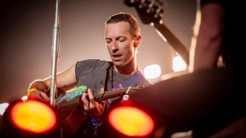 Chris Martin plays the guitar on the Pyramid Stage.