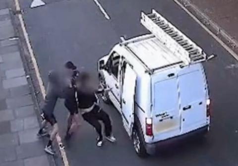 An ariel CCTV view of Havelock Road in Luton. A small white van with a ladder on the roof is stopped in the middle of the road, with a side door panel open. Next to the door, two men try to drag a third into the van. Their faces are all blurred out and you can see three pairs of feet. The victim wears black jogging bottoms with white stripes.