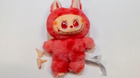 Fake Labubu toy, bright/pink colour, with bits fallen off.