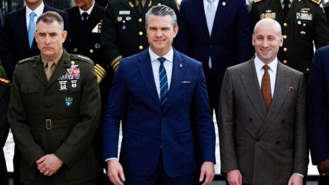 US Secretary of Defence Pete Hegseth standing in a blue suit and tie.