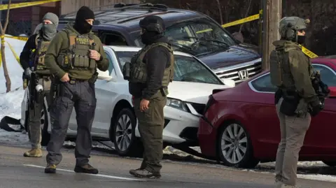 Members of U.S. Immigration and Customs Enforcement (ICE) stand at the scene after a driver of a vehicle was shot in Minneapolis,