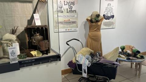 A selection of items included in the exhbition. They include some old clothes, a kettle, a watering can and a pram. 