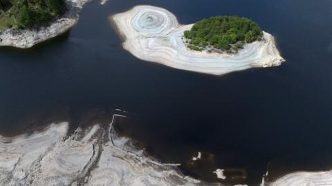 An aerial view of Haweswater reservoir, which shows receding water levels exposing light brown silt-beds.