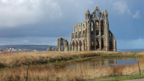 Whitby Abbey with cloud filed skies behind and water-logged land in front