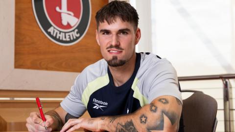 Ivan Mesik looks at the camera as he signs a contract in a Charlton Athletic office