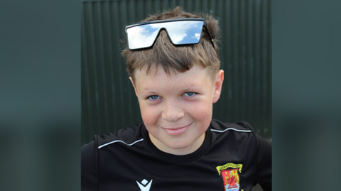 Leon Arundel smiling at the camera. He is wearing a black shirt and glasses