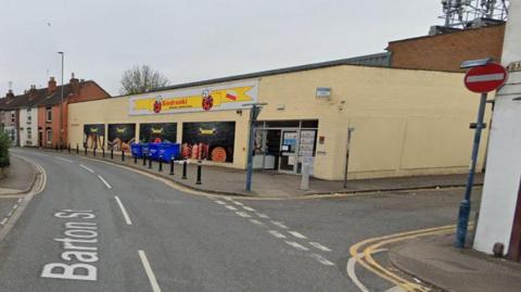 A view of a street with Biedronki shop. The street sign for Barton Street is visible and a no entry sign.