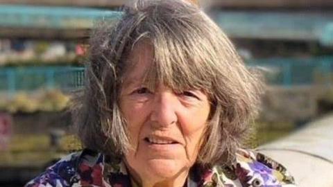 Woman with grey hair wearing floral jacket