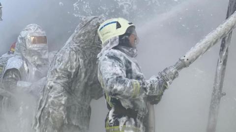 Three firefighters extinguishing a blaze at a Ukrainian energy plant. 