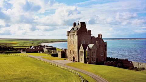 A picture of the tower, with grass on one side and the sea on the other.