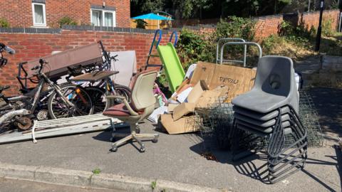 Chairs, a garden slide and cardboard among a pile of items ready for disposal on a street in Sheffield.
