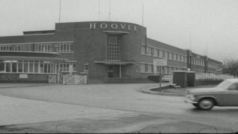 A black and white photo of the outside of a large building with many windows and the word 'Hoover' across the front.