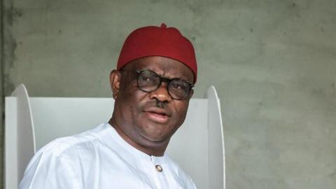 Federal capital territory minister in Nigeria, Nyesom Wike wearing a white traditional dress, red Igbo cap and glasses