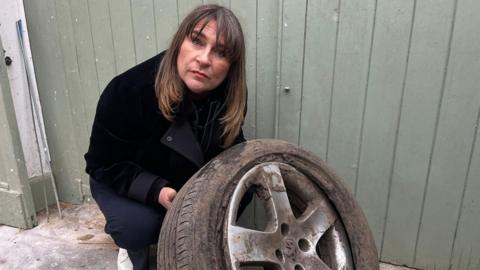 Sarah Gray holding a burst tyre