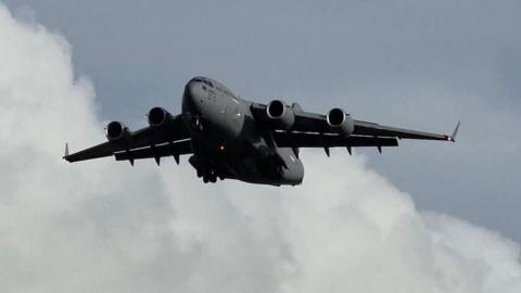  A large grey US Air Force military jet aircraft against a cloudy grey blue sky above a telegraph wire on Prestwick.