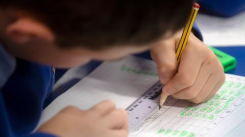 Child writing in school textbook