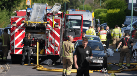 Fire engine and ambulance in a street with emergency service personnel in foreground 