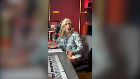 Fearne Cotton has a long blonde hair. She has her mouth open in surprise. She is a wearing a blue patterned cardigan.