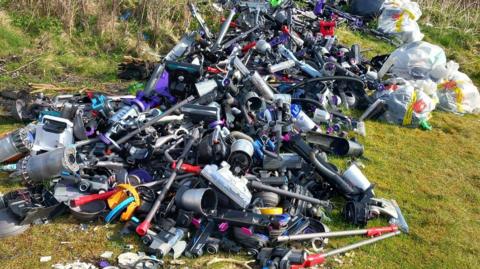 A heap of discarded vacuums on a hillside.