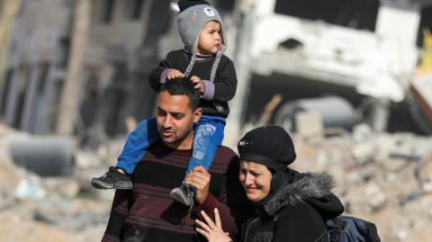 Displaced Palestinians walk past the rubble as they attempt to return to their homes, following a delay in the ceasefire between Israel and Hamas over the hostage list