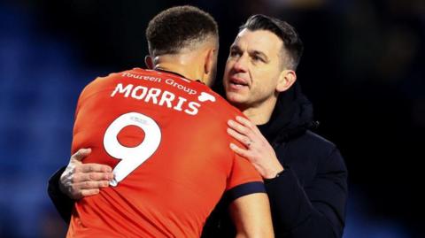 Luton Town centre forward Carlton Morris and head coach Matt Bloomfield embrace each other post-match