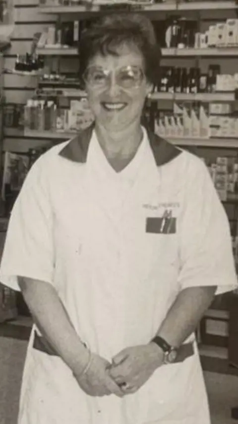 Black and white image of Sadie in her white pharmacist's uniform. 