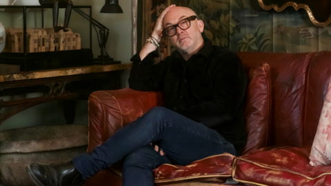 A man wearing glasses sitting on a sofa 