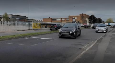 A car driving a speed hump that covers half of a road