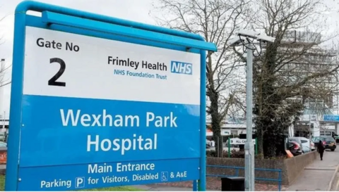 A sign outside Wexham Park Hospital and a building to the right of it.