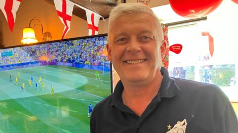 Landlord standing in front of TV showing Euros