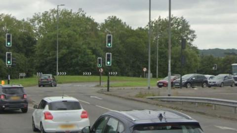 Cars approaching a large roundabout from different directions. 