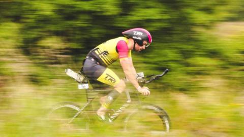 A cyclist speeds through the countryside on a bike.