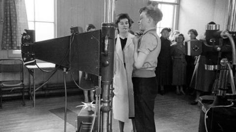 A line of people wait for X-rays at a Glasgow hospital during an epidemic of tuberculosis in 1957