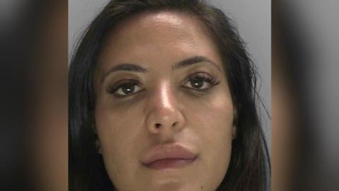 A custody mugshot of Anita Mirmohammadi. She has dark hair and a blank expression on her face.