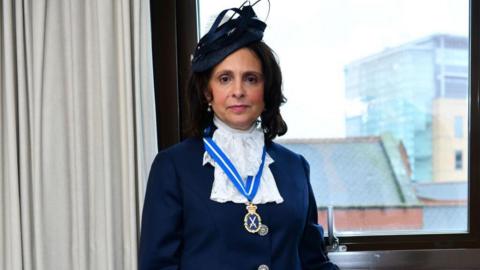 A woman in ceremonial clothing and hat