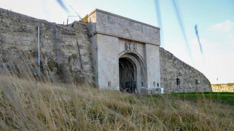 A general view of HMP The Verne, a stone arch built into a stone wall, which serves as the entrance to the prison.