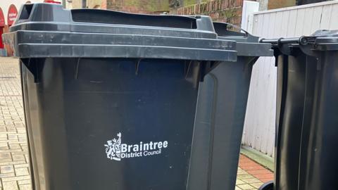 Three black bins on a paved town centre street in Braintree.