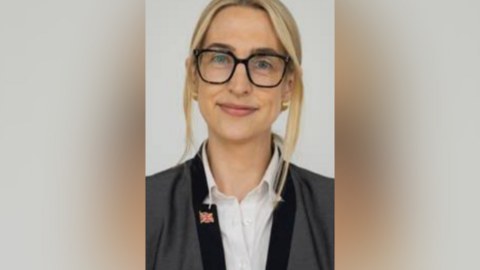 A woman with long blonde hair wearing glasses