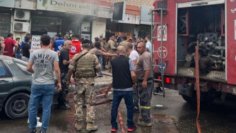 People and first responders gather at the scene of a reported device explosion in Sidon, in southern Lebanon (18 September 2024)