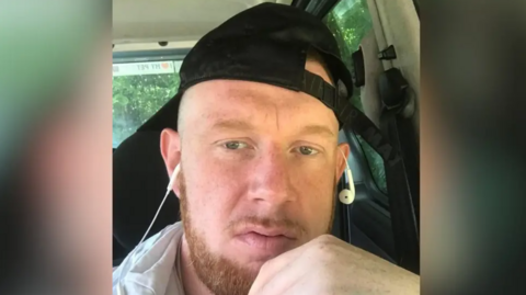 Louis Howard with a white headphone hung around his ears and a black cap facing backwards