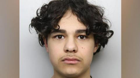 A custody picture of Bardia Shojaeifard, a teenage boy with dark curly hair.
