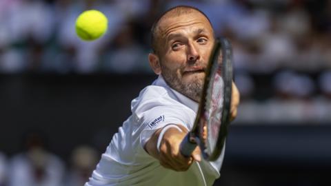 Dan Evans stretches to hit a backhand volley
