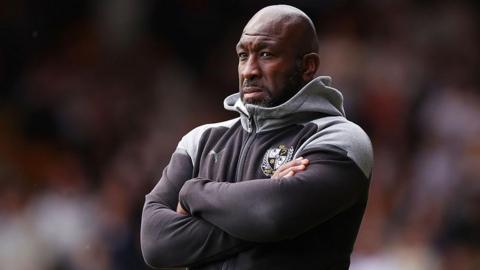 Port Vale manager Darren Moore stands with arms folded looking on during a match